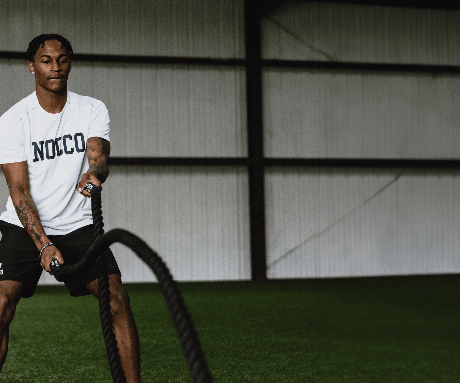 Man exercising with battle ropes in a gym.