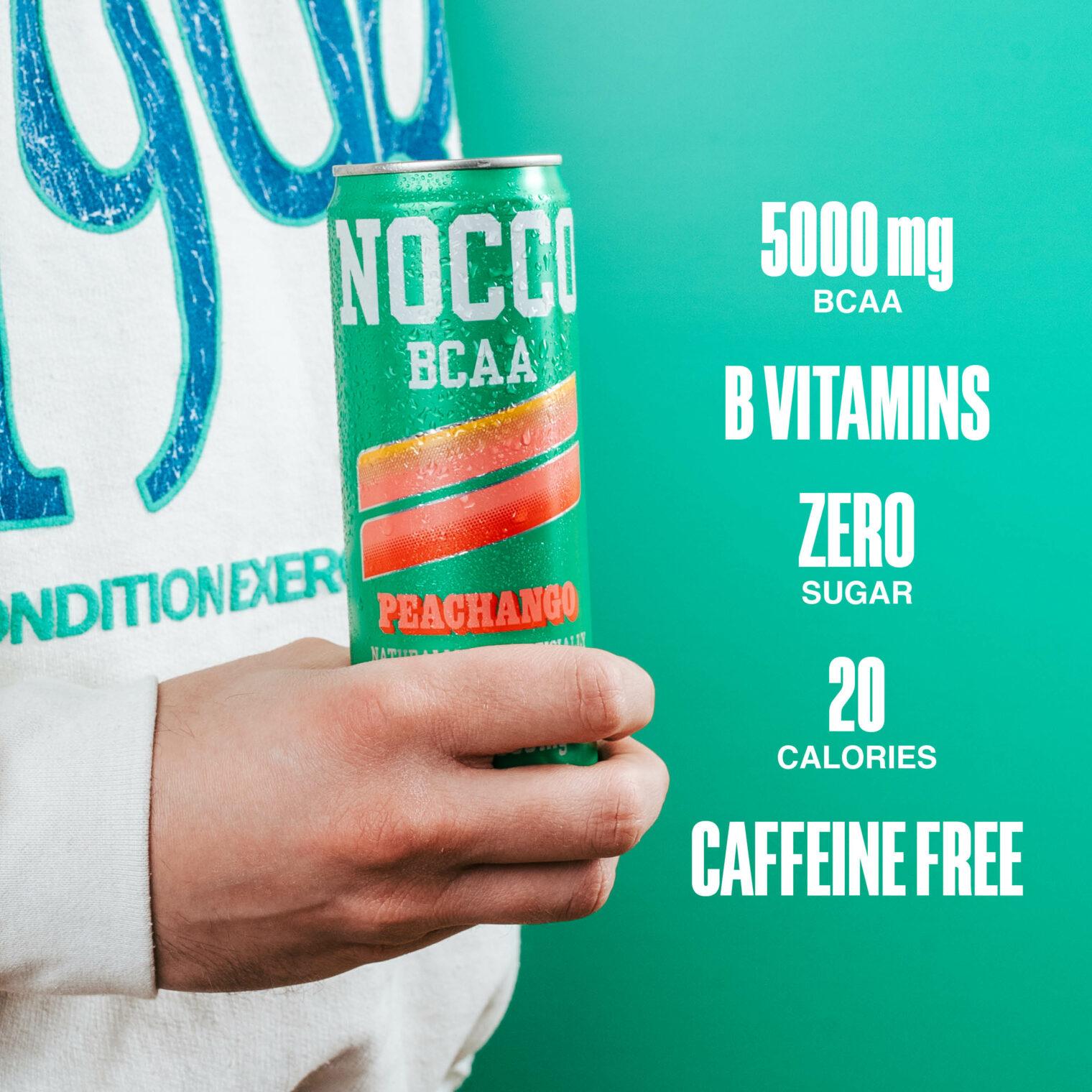 Person holding a NOCCO BCAA Peachango drink can against a green background.